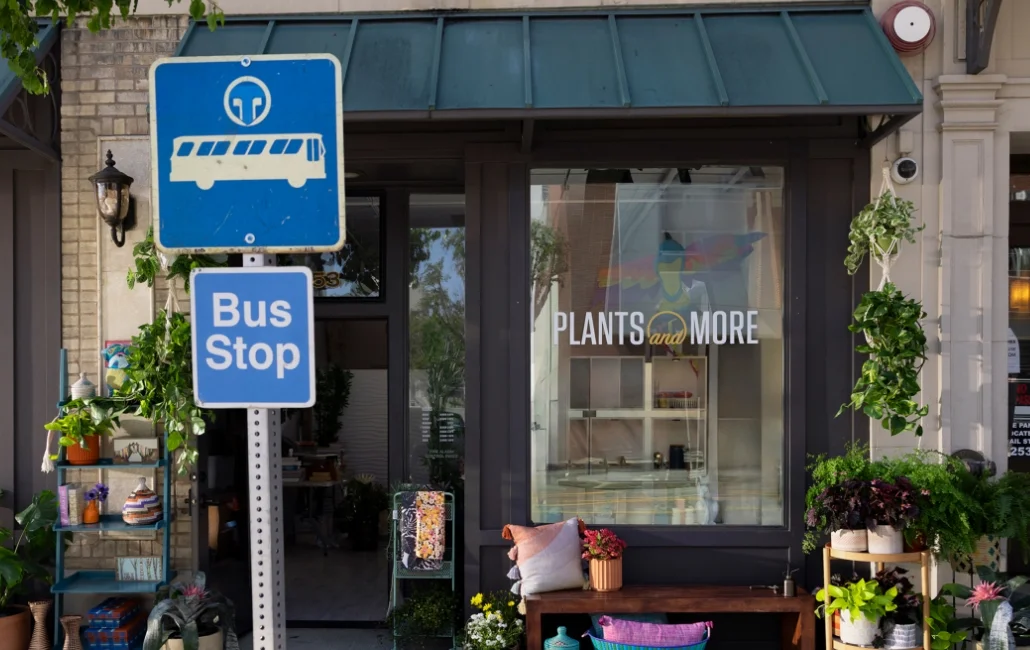 A bus stop sign in front of a plant store