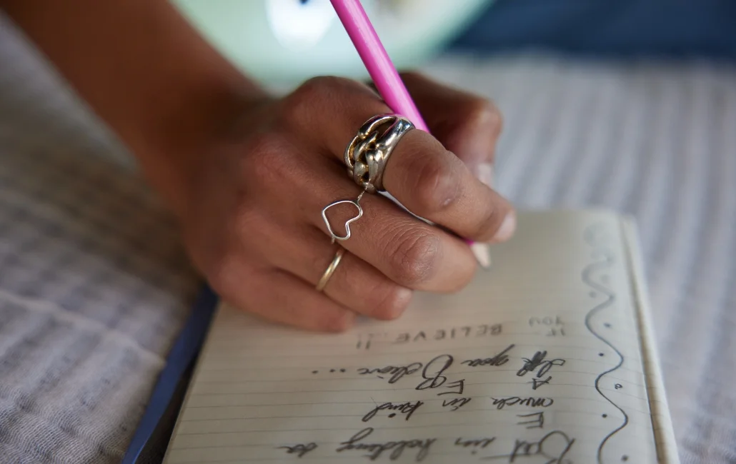 Close up of a woman's hand writing in a notebook